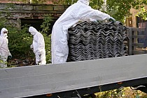 Zdjęcie przedstawia osoby w kombinezonach pakujące odpady azbestowe