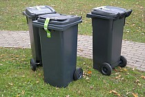 Zdjęcie przedstawia czarne pojemniki na odpady